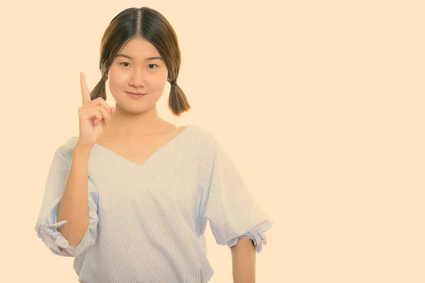 젊고 아름다운 아시아 여성 이 손가락을 들고 찍은 스튜디오 촬영 — 스톡 사진