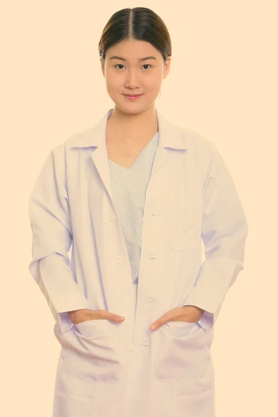 Зйомки молодого прекрасного азіатського лікаря, який стоїть з руками на кишенях. — стокове фото
