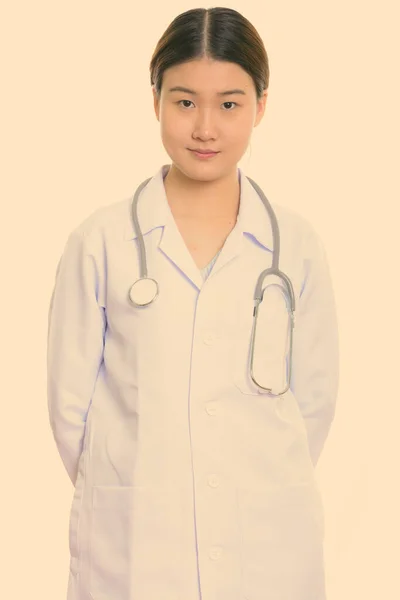 Studio colpo di giovane bella donna asiatica medico con le mani sulla schiena — Foto Stock
