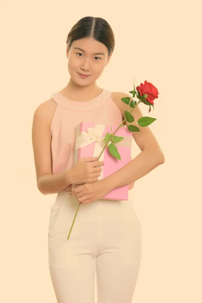 Młoda piękna Azjatka trzyma czerwoną różę i pudełko prezentów gotowe na Walentynki — Zdjęcie stockowe