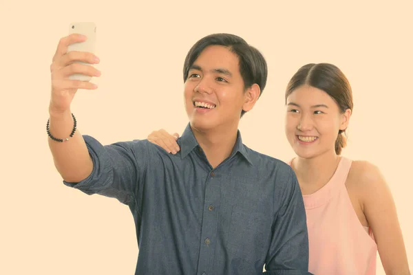 Joven feliz pareja asiática sonriendo mientras toma foto selfie con el teléfono móvil junto con el hombre tomando la foto — Foto de Stock