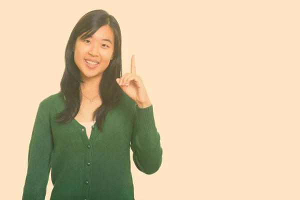 Jovem mulher asiática feliz apontando dedo para cima — Fotografia de Stock