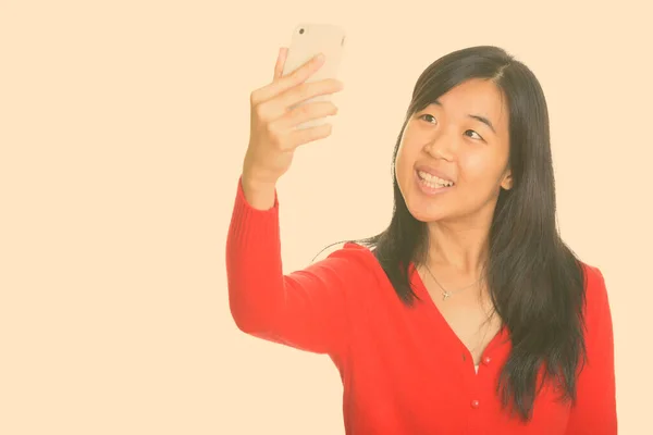 Young happy Asian woman taking selfie with mobile phone — Stock Photo, Image