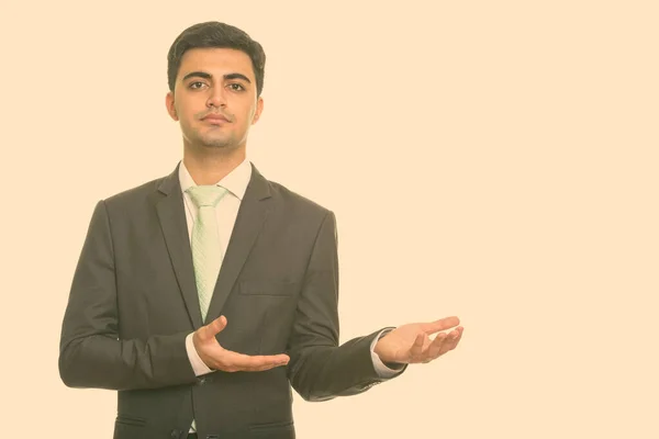 Portrait of young handsome Persian businessman in suit showing something — Stock Photo, Image