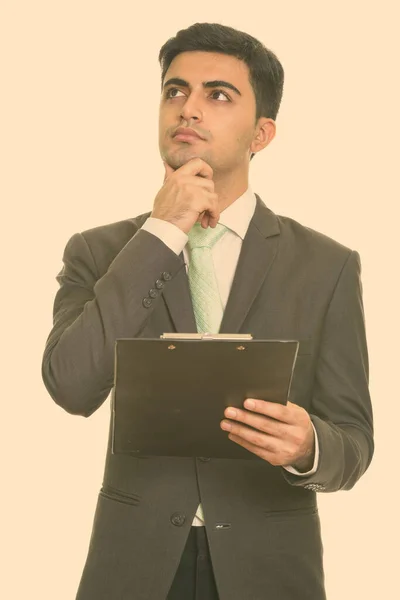 Jonge knappe Perzische zakenman lezen klembord terwijl denken — Stockfoto