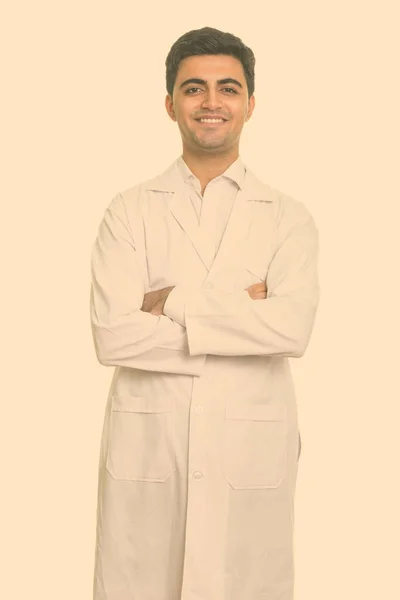 Портрет счастливого молодого красивого персидского врача, улыбающегося со скрещенными руками — стоковое фото