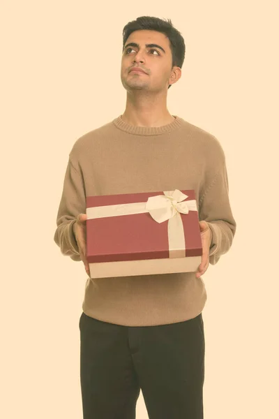 Jovem bonito homem persa segurando caixa de presente enquanto pensa pronto para o dia dos namorados — Fotografia de Stock