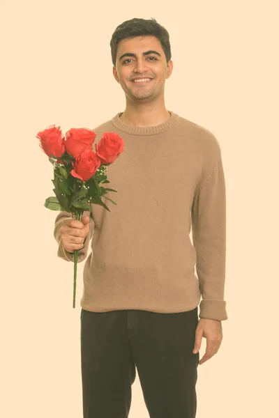 Joven hombre persa feliz sosteniendo rosas rojas listo para el día de San Valentín — Foto de Stock