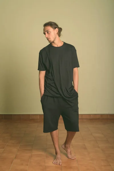 Jonge knappe man draagt zwart shirt tegen gekleurde achtergrond — Stockfoto