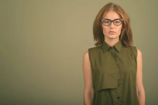 Young woman wearing green sleeveless top and eyeglasses against colored background — Stock Photo, Image