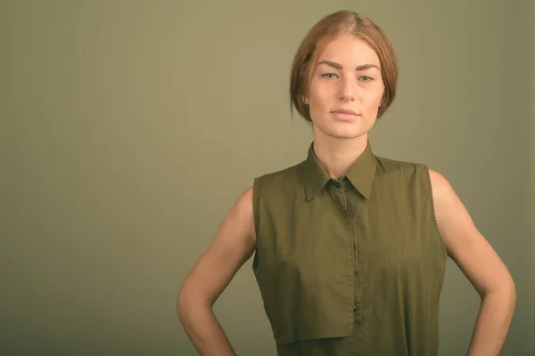Jonge vrouw draagt groene mouwloze top tegen gekleurde achtergrond — Stockfoto