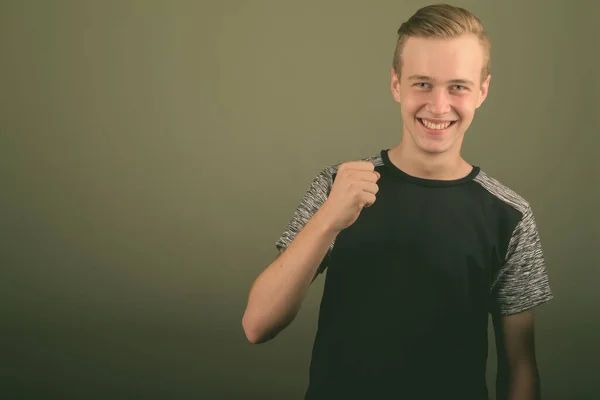 Junger schöner Mann mit blonden Haaren vor farbigem Hintergrund — Stockfoto