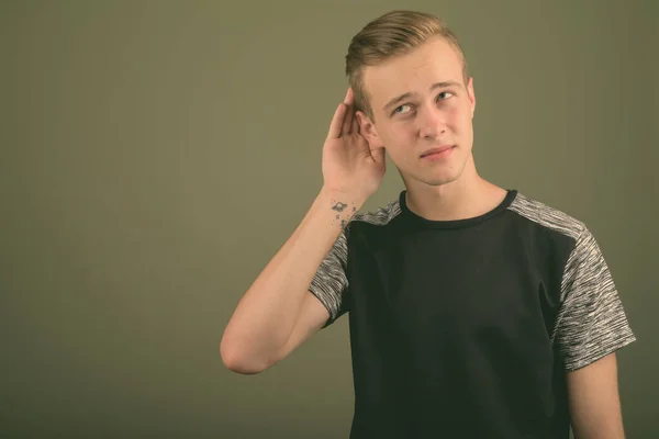 Junger schöner Mann mit blonden Haaren vor farbigem Hintergrund — Stockfoto