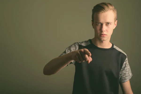 Junger schöner Mann mit blonden Haaren vor farbigem Hintergrund — Stockfoto