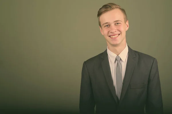 Junger gutaussehender Geschäftsmann im Anzug vor farbigem Hintergrund — Stockfoto