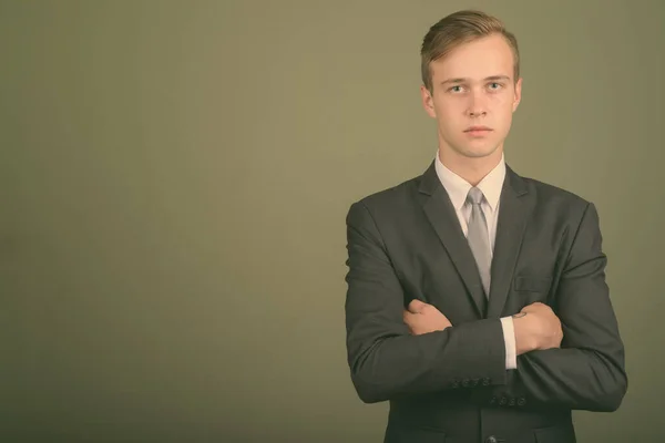 Young handsome businessman wearing suit against colored background — Stock Photo, Image