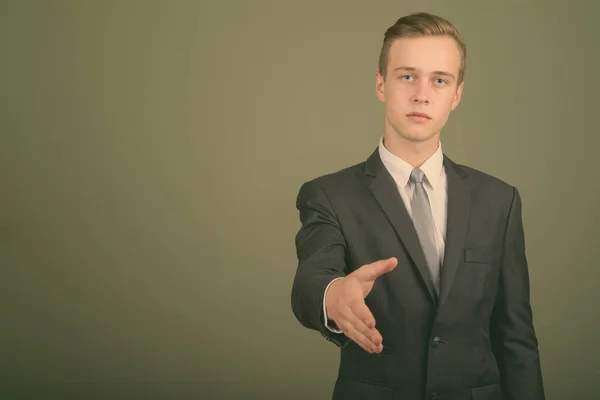Junger gutaussehender Geschäftsmann im Anzug vor farbigem Hintergrund — Stockfoto