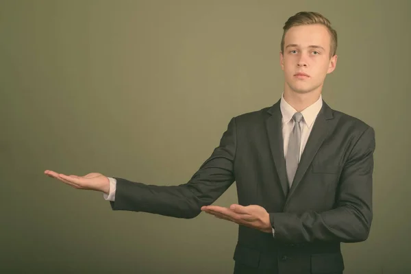 stock image Young handsome businessman wearing suit against colored background