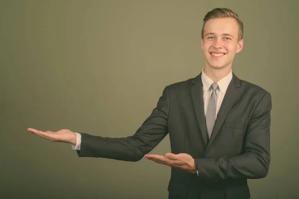 Nuori komea liikemies yllään puku vastaan värillinen tausta — kuvapankkivalokuva