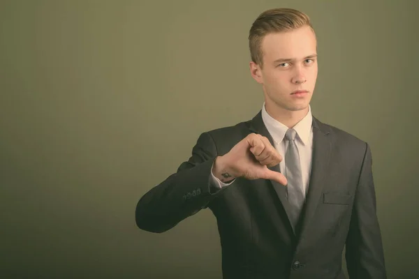 Young handsome businessman wearing suit against colored background — Stock Photo, Image