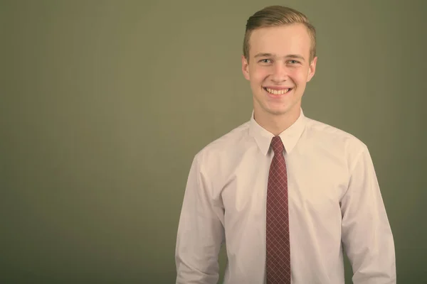 Junger gutaussehender Geschäftsmann mit blonden Haaren vor farbigem Hintergrund — Stockfoto