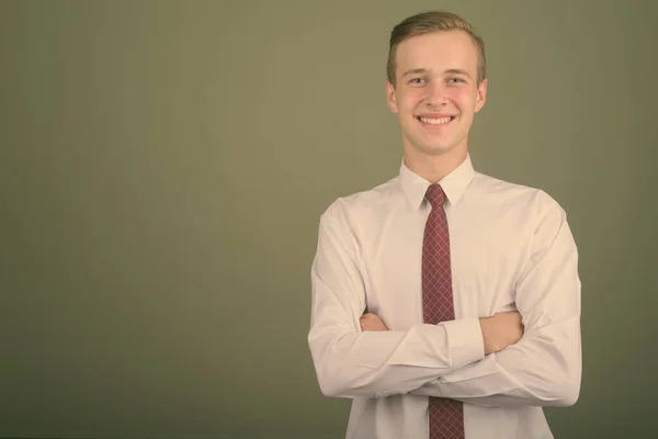 Junger gutaussehender Geschäftsmann mit blonden Haaren vor farbigem Hintergrund — Stockfoto