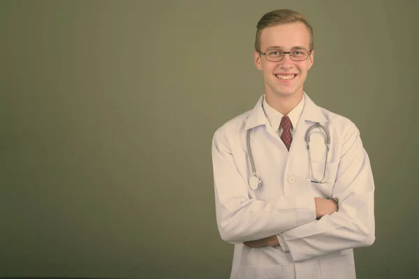 Νεαρός όμορφος άντρας γιατρός σε έγχρωμο φόντο — Φωτογραφία Αρχείου