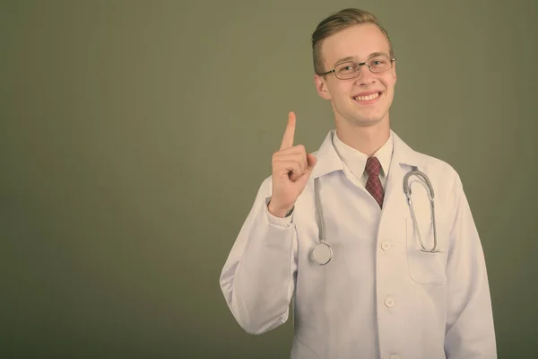 Jovem bonito homem médico contra fundo colorido — Fotografia de Stock