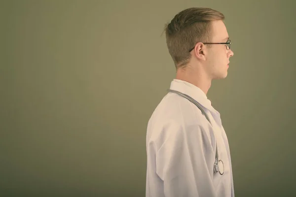 Young handsome man doctor against colored background — Stock Photo, Image