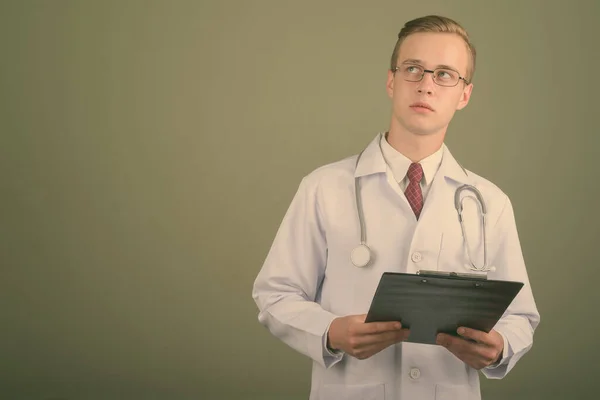 Jovem bonito homem médico contra fundo colorido — Fotografia de Stock