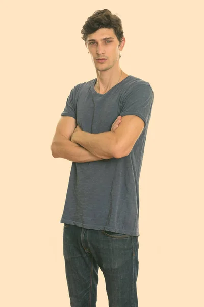 Studio shot of young handsome man standing with arms crossed — Stock Photo, Image