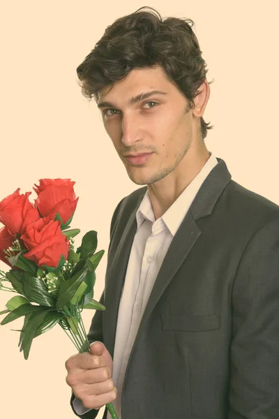 Studioaufnahme eines jungen, gut aussehenden Geschäftsmannes mit roten Rosen — Stockfoto