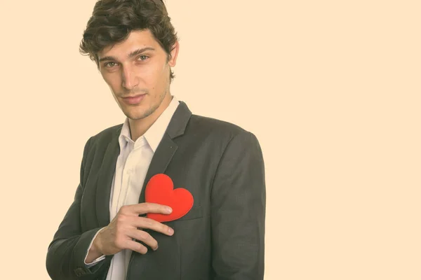 Studioaufnahme eines jungen, gut aussehenden Geschäftsmannes mit rotem Herz an der Brust — Stockfoto