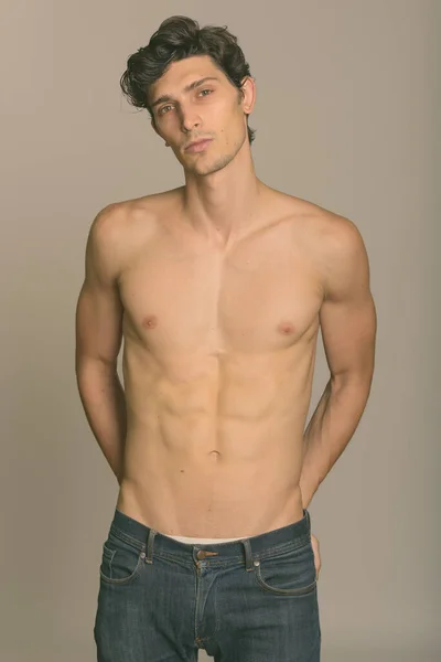 Studio shot of young handsome man shirtless with hands on back pocket — Stock Photo, Image