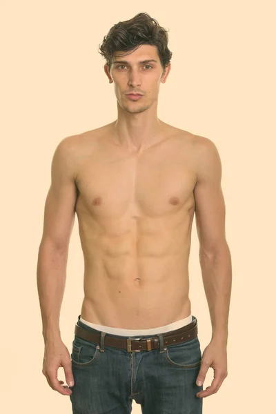 Studio shot of young handsome man standing shirtless — Stock Photo, Image