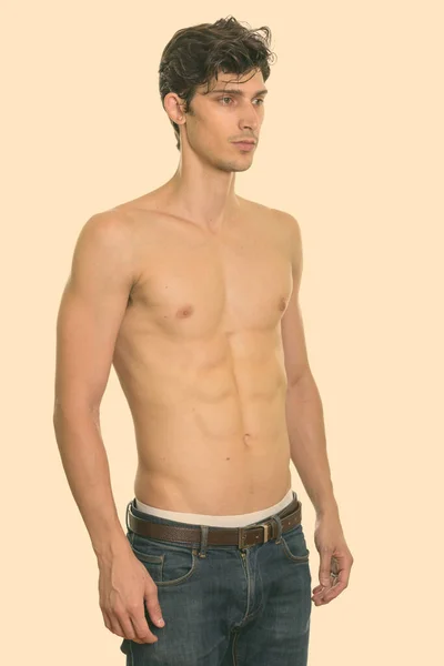 Studio záběr mladého pohledného muže stojící a dívající se na pravé tričko bez — Stock fotografie