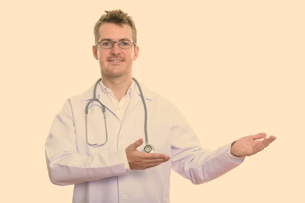 Студийный снимок счастливого человека доктор улыбается, показывая что-то — стоковое фото
