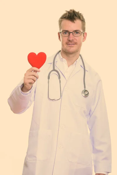 Estúdio tiro de homem feliz médico sorrindo enquanto segurando coração vermelho — Fotografia de Stock