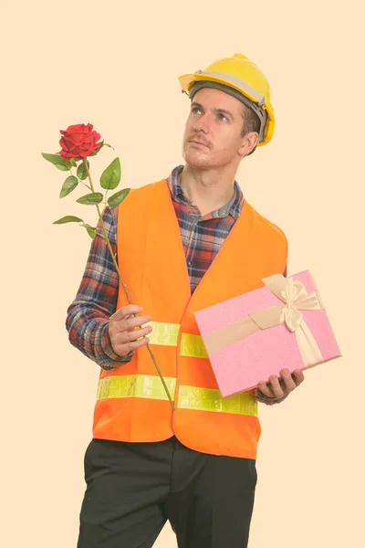 Nachdenklicher Mann Bauarbeiter hält rote Rose und Geschenkbox für Valentinstag bereit — Stockfoto