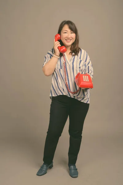 Gammal vacker asiatisk affärskvinna mot grå bakgrund — Stockfoto