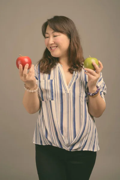 Zralý krásný asijské businesswoman proti šedé pozadí — Stock fotografie