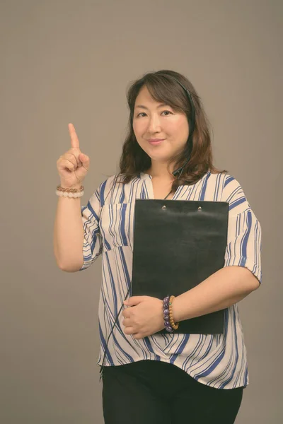 Maturo bella donna d'affari asiatica contro sfondo grigio — Foto Stock