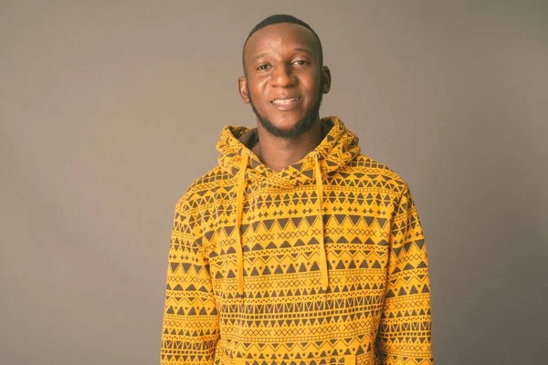 Jovem e bonito homem africano com cabelo curto contra fundo cinza — Fotografia de Stock