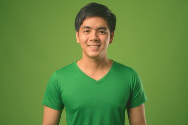 Genç yakışıklı Filipinli adam yeşil arka plana karşı