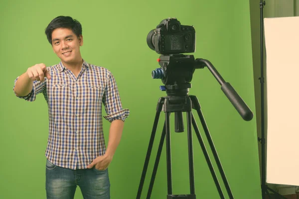 Junger hübscher philippinischer Mann vor grünem Hintergrund — Stockfoto