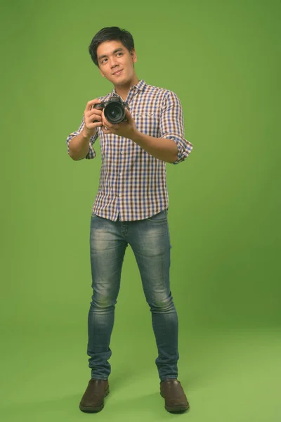 Fiatal jóképű filippínó férfi zöld háttér — Stock Fotó