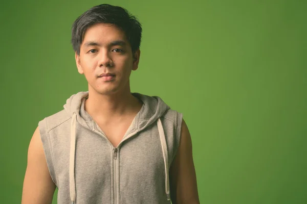 Young handsome Filipino man against green background