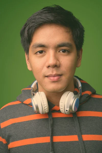 Young handsome Filipino man against green background — Stock Photo, Image