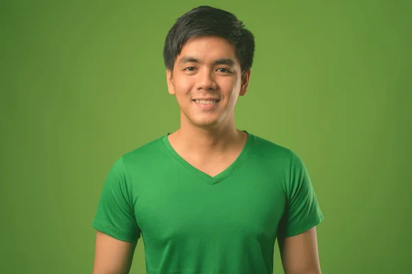 Jonge knappe Filipijnse man tegen groene achtergrond — Stockfoto