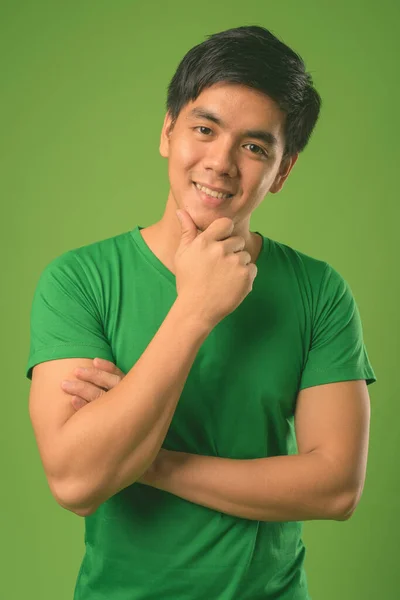 Młody przystojny Filipino człowiek na zielonym tle — Zdjęcie stockowe